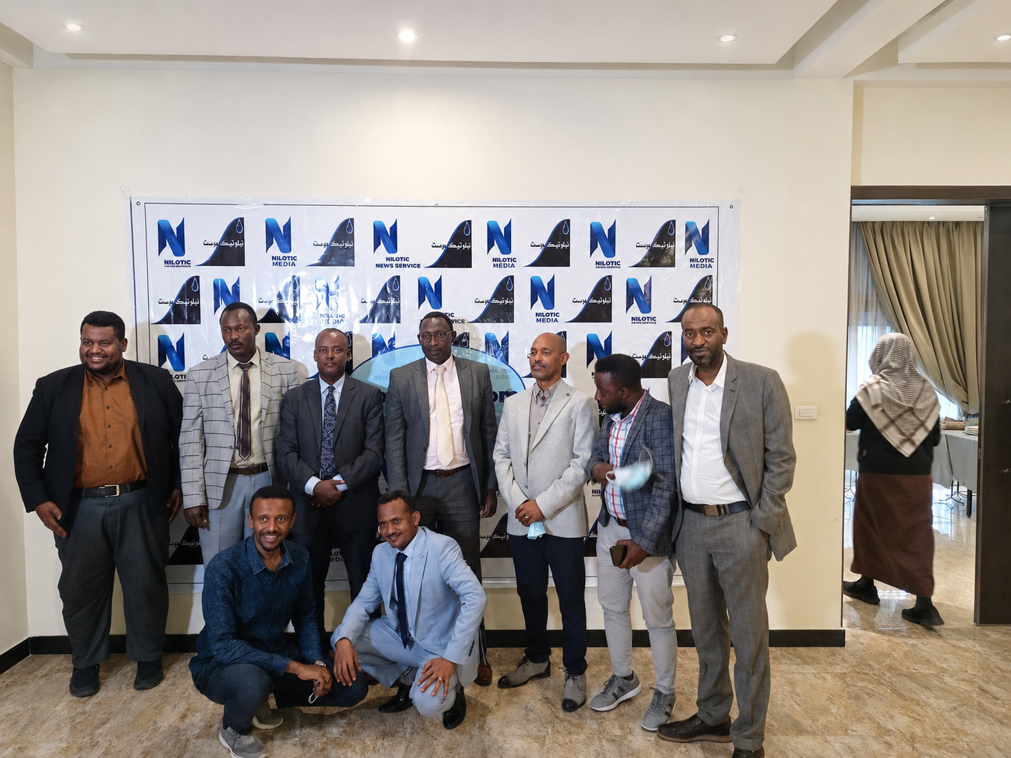 Group photograph in front of a Nilotic Media and Nilotic News Service branded backdrop.