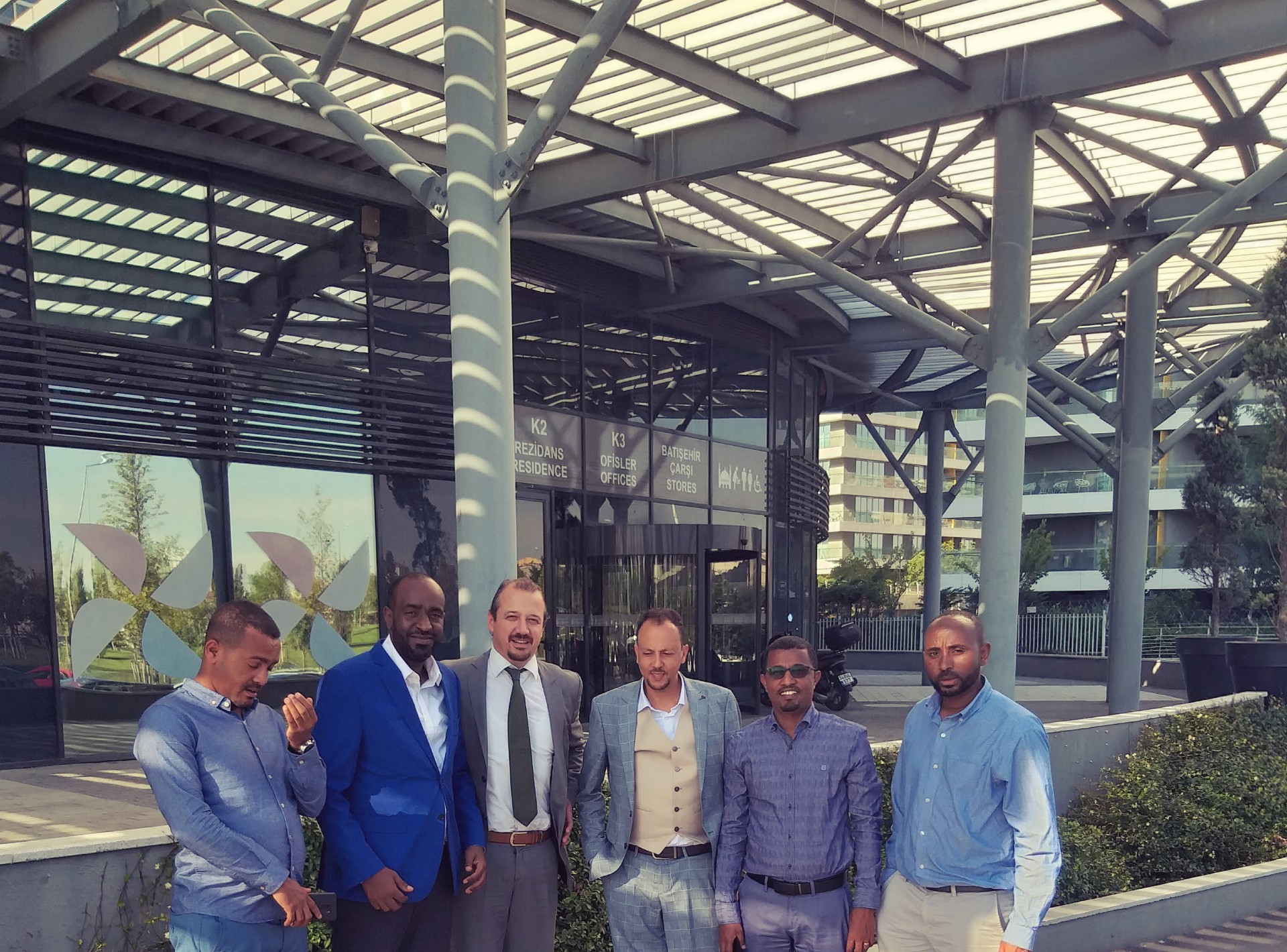 Group of business visitors standing outside the entrance of a modern office and residence complex.