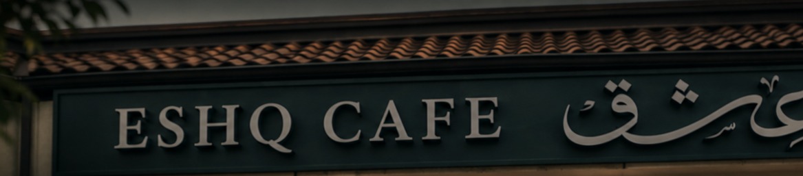 Exterior signage of the ESHQ Cafe carrying the English ESHQ wordmark and the Arabic عشق calligraphy