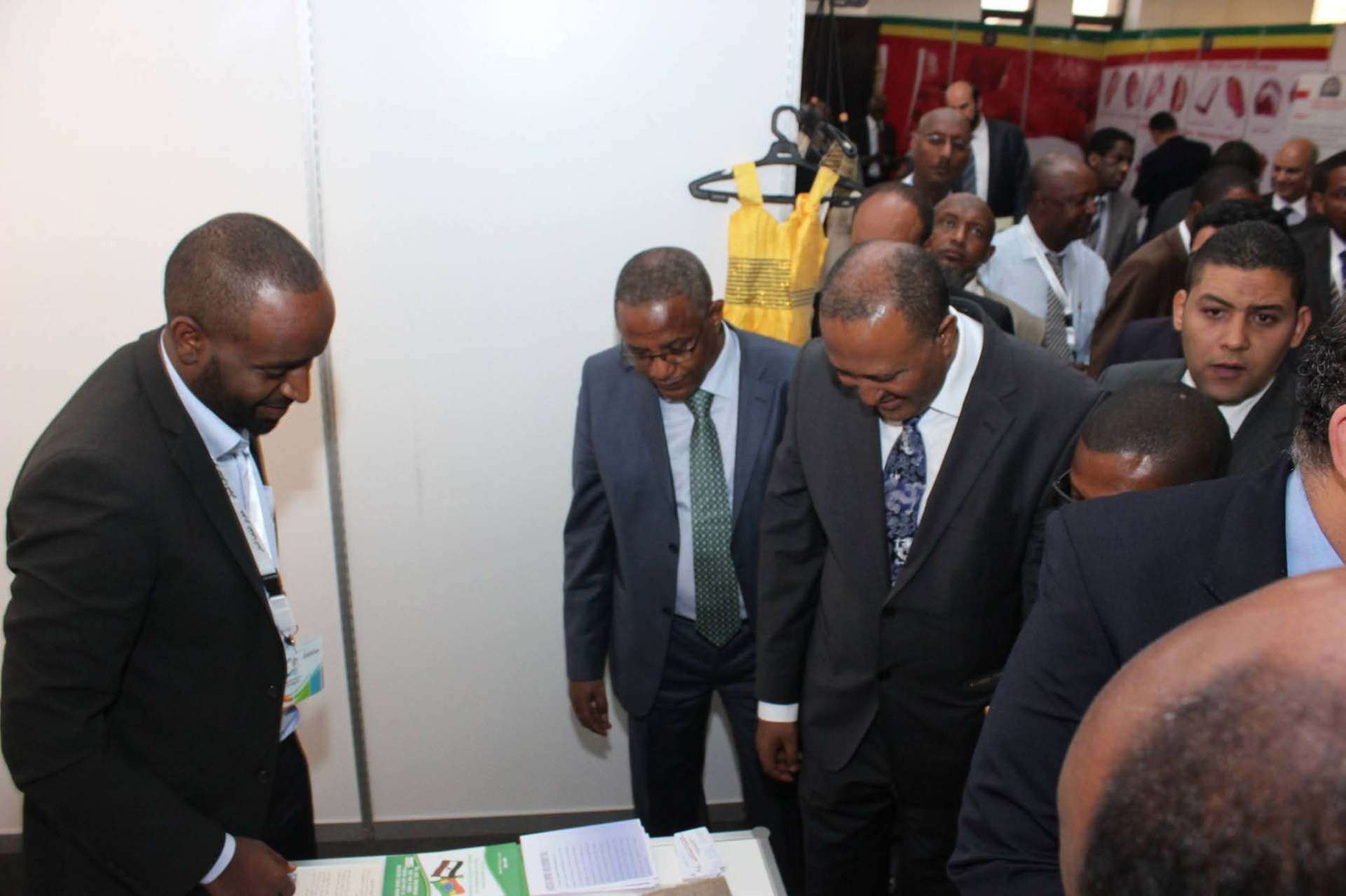 Exhibition stand briefing with visiting delegates reviewing printed product and market material.