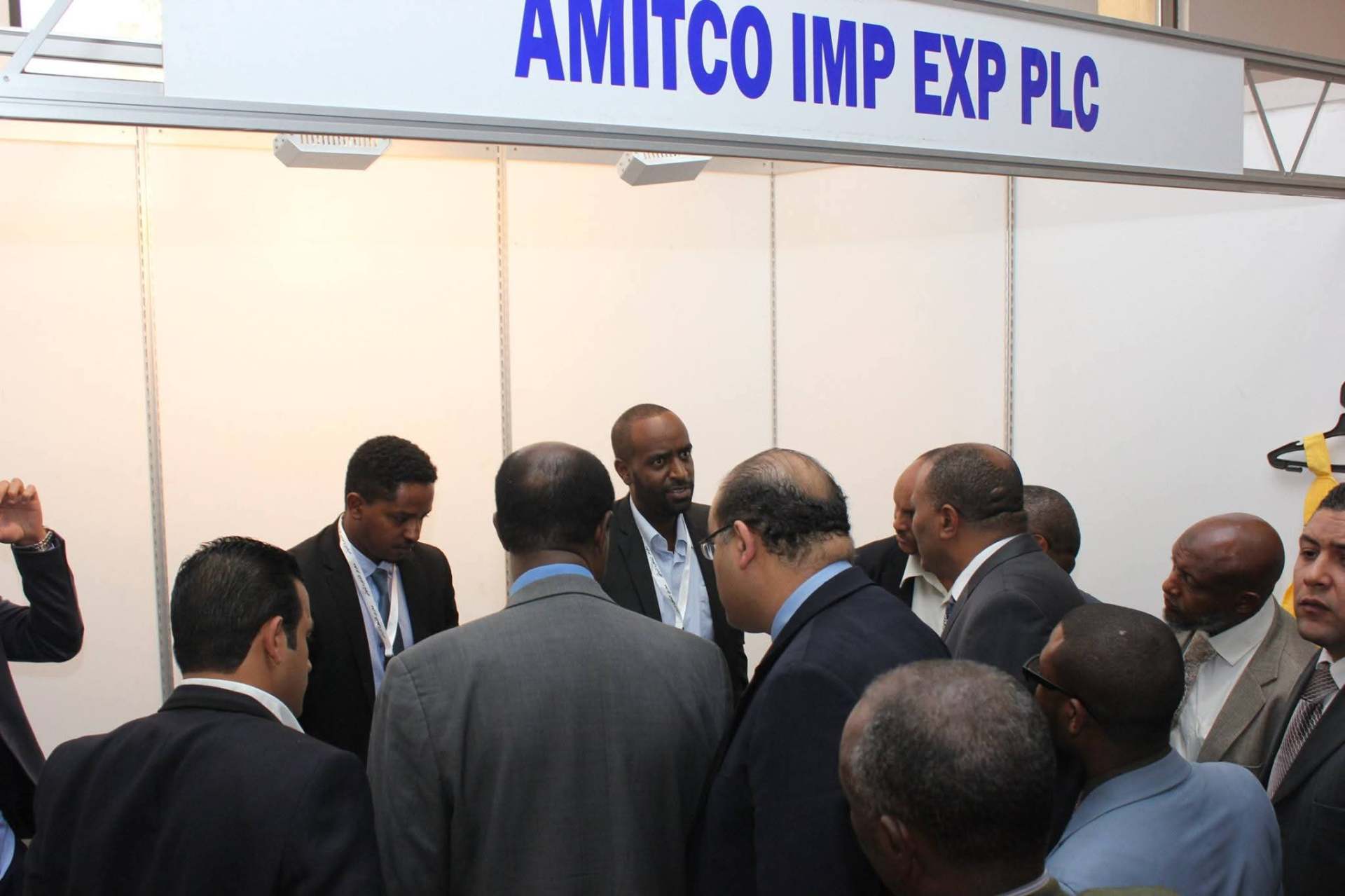 Abdulmuen Mohamed in conversation with a group of visitors beneath an AMITCO IMP EXP PLC exhibition stand sign.